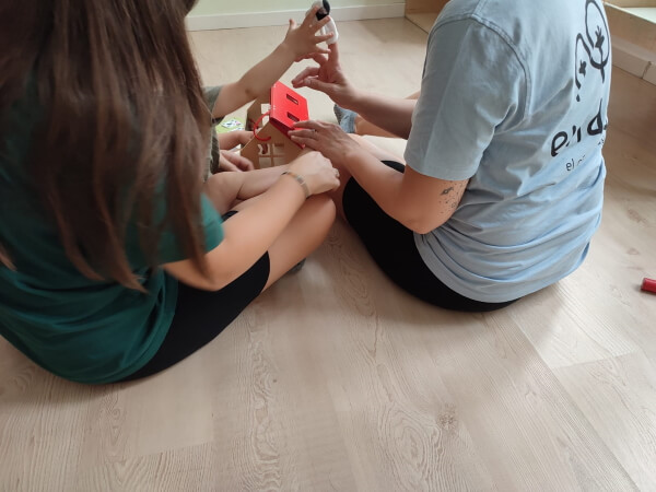 Dos educadoras de enDara crean vínculos con una niña para facilitar el periodo de adatpación. Estan jugando sentadas en el suelo con ella.